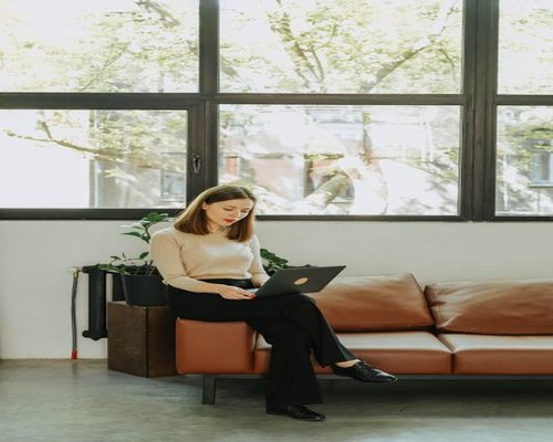 Young professional working comfortably on a laptop near a large window in Lima